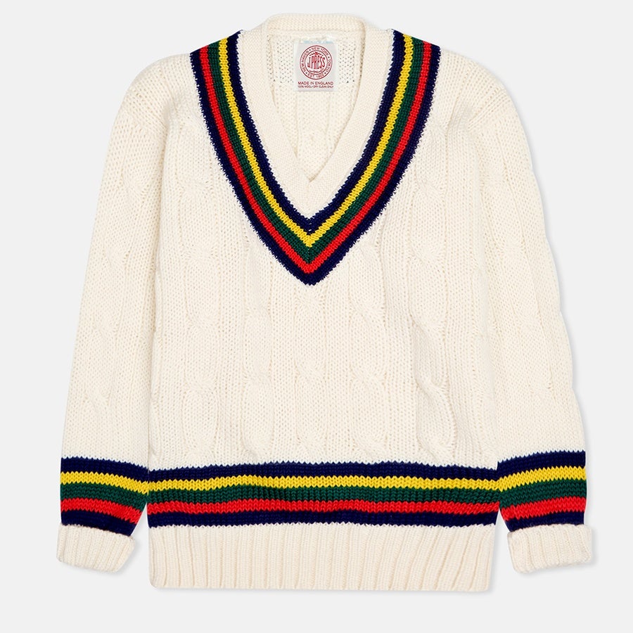 Cream-colored cable knit sweater with a deep V-neckline featuring navy, green, yellow, and red stripes. The same striped pattern is repeated on the cuffs and hem. The sweater has a ribbed hem and cuffs.