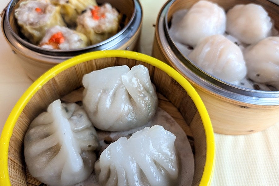 Three steamer baskets hold three different times of Chinese dumplings.