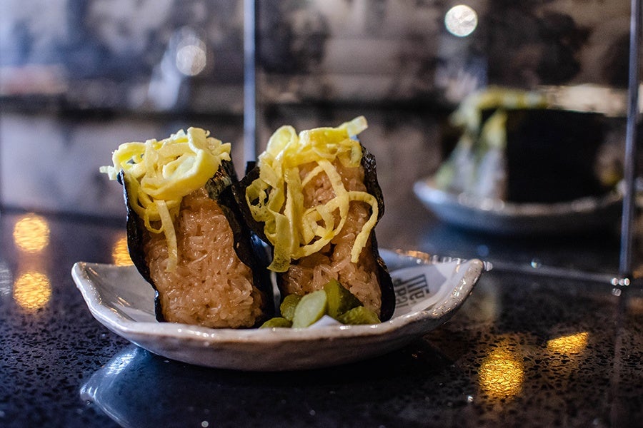 Japanese-style clumps of rice in a seaweed wrapper are topped with thin egg strips.