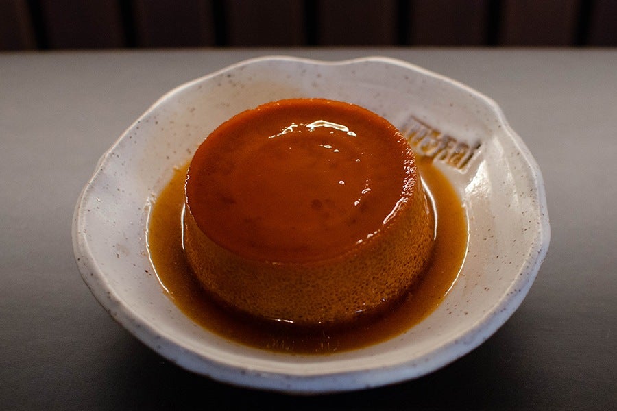 An orange flan sits on a white plate.