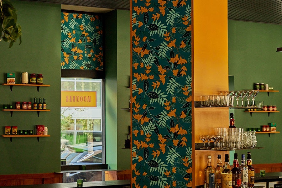 A bar at a restaurant with tropical wallpaper and green walls.