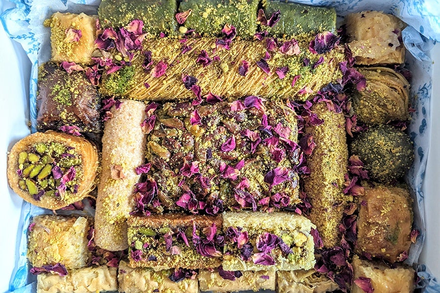 Overhead view of a box of Middle Eastern sweets covered with bits of dried rose petals.